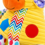 Pormenor da textura macia e padrões coloridos do peluche sensorial girafa.