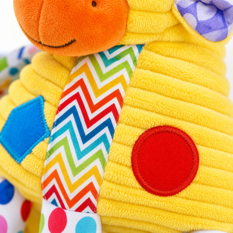 Pormenor da textura macia e padrões coloridos do peluche sensorial girafa.