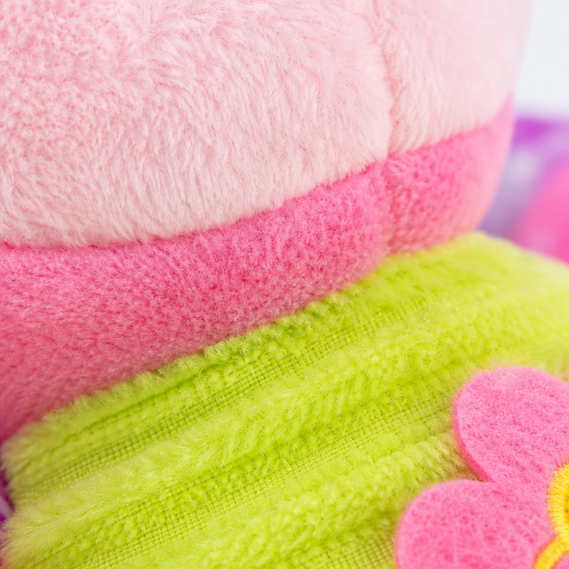 Pormenor da textura macia e cores vibrantes do peluche sensorial de borboleta.