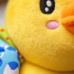 Pormenor da textura macia e acabamentos de qualidade do peluche passarinho de atividades.