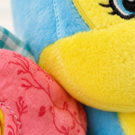 Pormenor das texturas e qualidade do tecido macio do peluche de atividades para bebé.