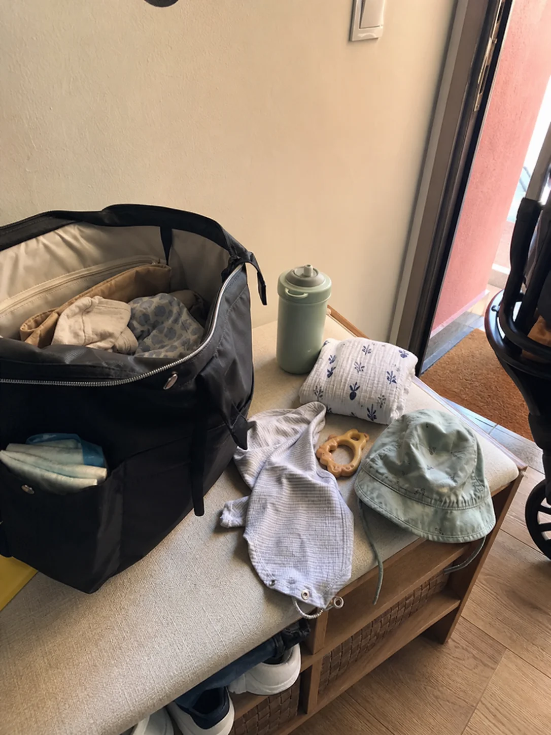Mala de bebé aberta com essenciais junto à porta de casa