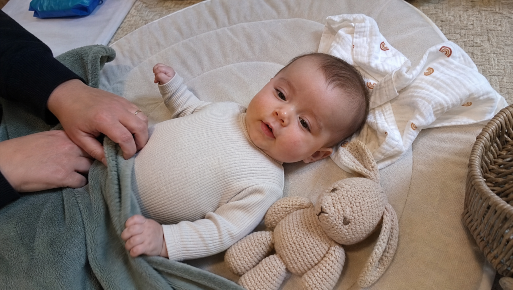 Bebé num tapete de brincar em casa com brinquedo de crochet