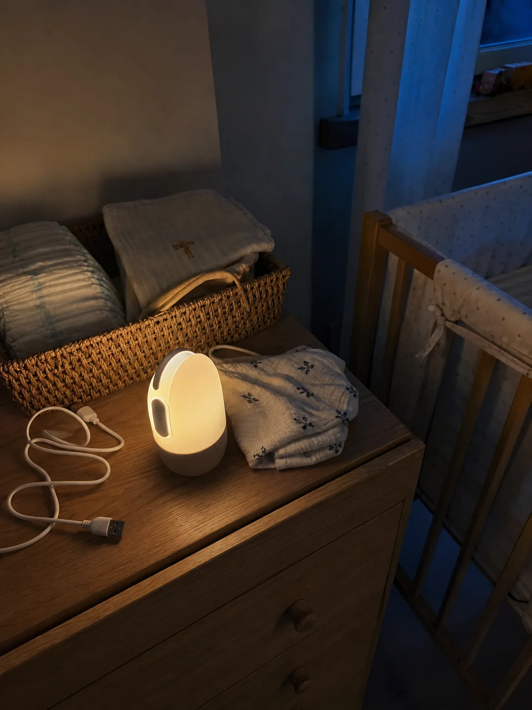 Luz de presença recarregável acesa sobre cómoda no quarto do bebé