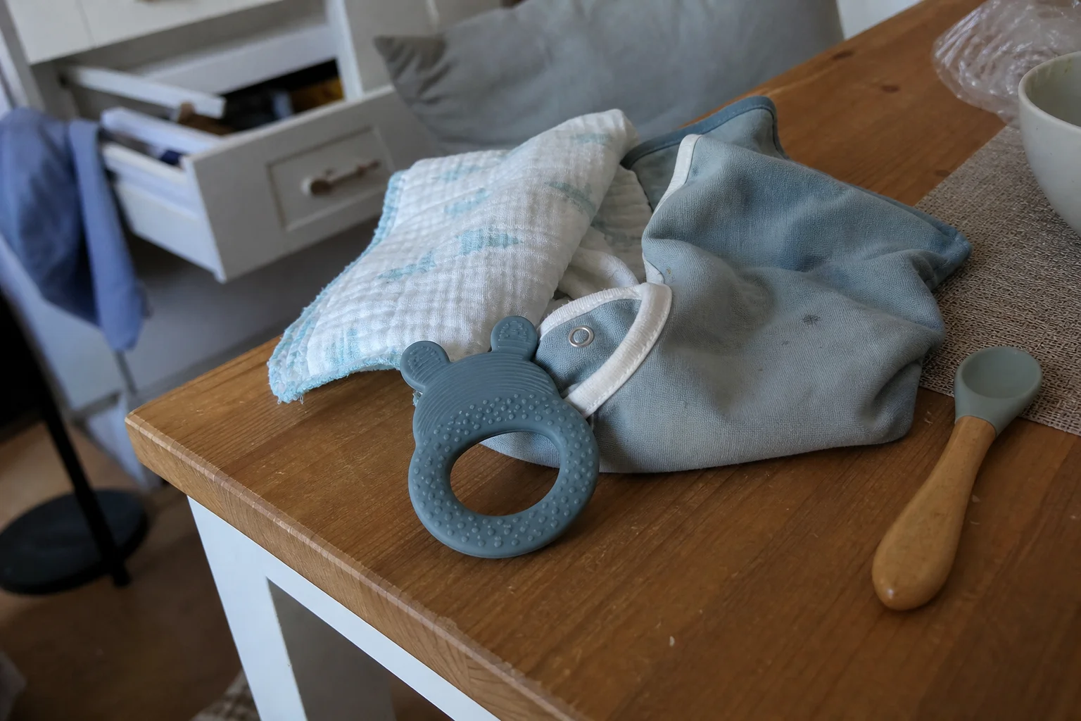 Mordedor para bebé que não larga as mãos numa mesa real com babete e fralda de pano