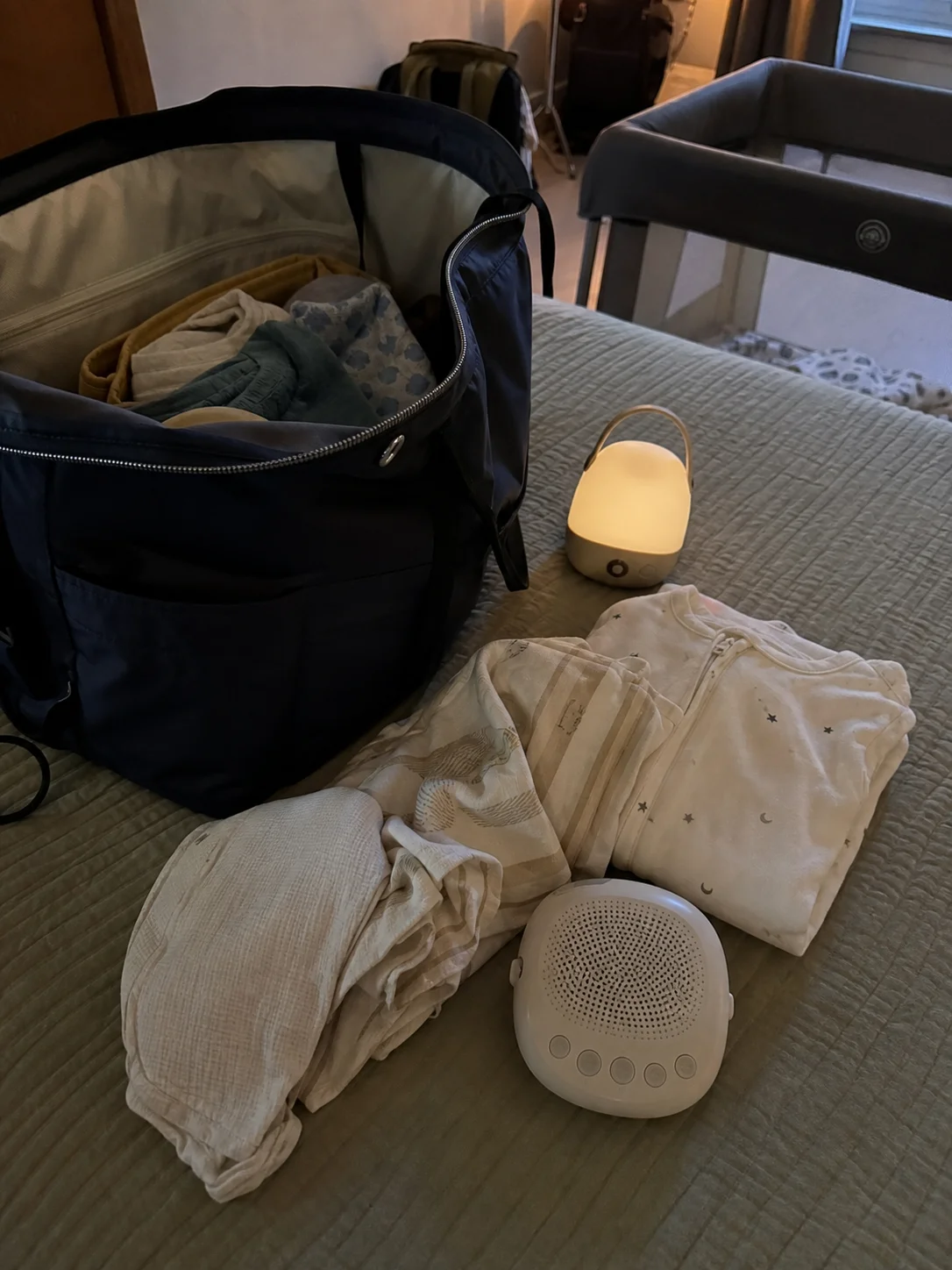 Mala de viagem com roupa de bebé, luz pequena e máquina de ruído branco